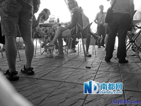 泰国一景区购物点外，中国游客围在一起等候，现场闹哄哄，地上散落着包装纸、烟头等杂物。 ...